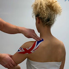PHYSIO TAPING A WOMANS SHOULDER WITH KINESIOTAPE