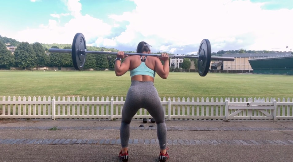 WOMAN SQUATTING WITH A BARBELL